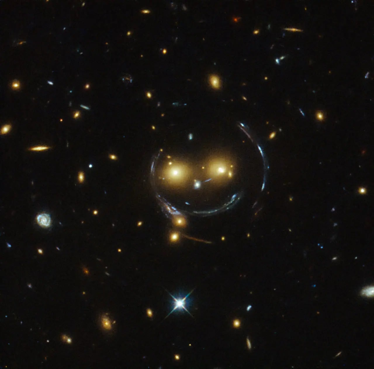 Hubble'dan Kozmik Gülümseme: Kütleçekimsel Merceklenme ile Şekillenen Galaksi Kümesi